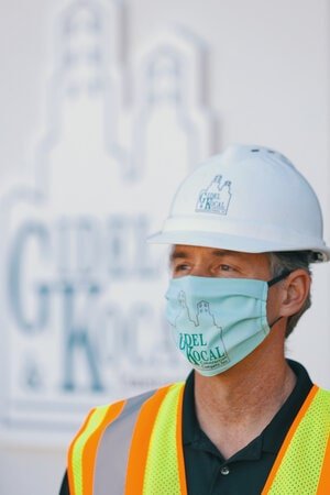 Man wearing a high-viz vest, facemask and white hardhat